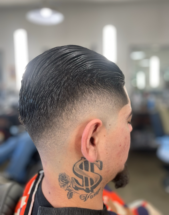 Slicked-back haircut with a clean skin fade by Daniel