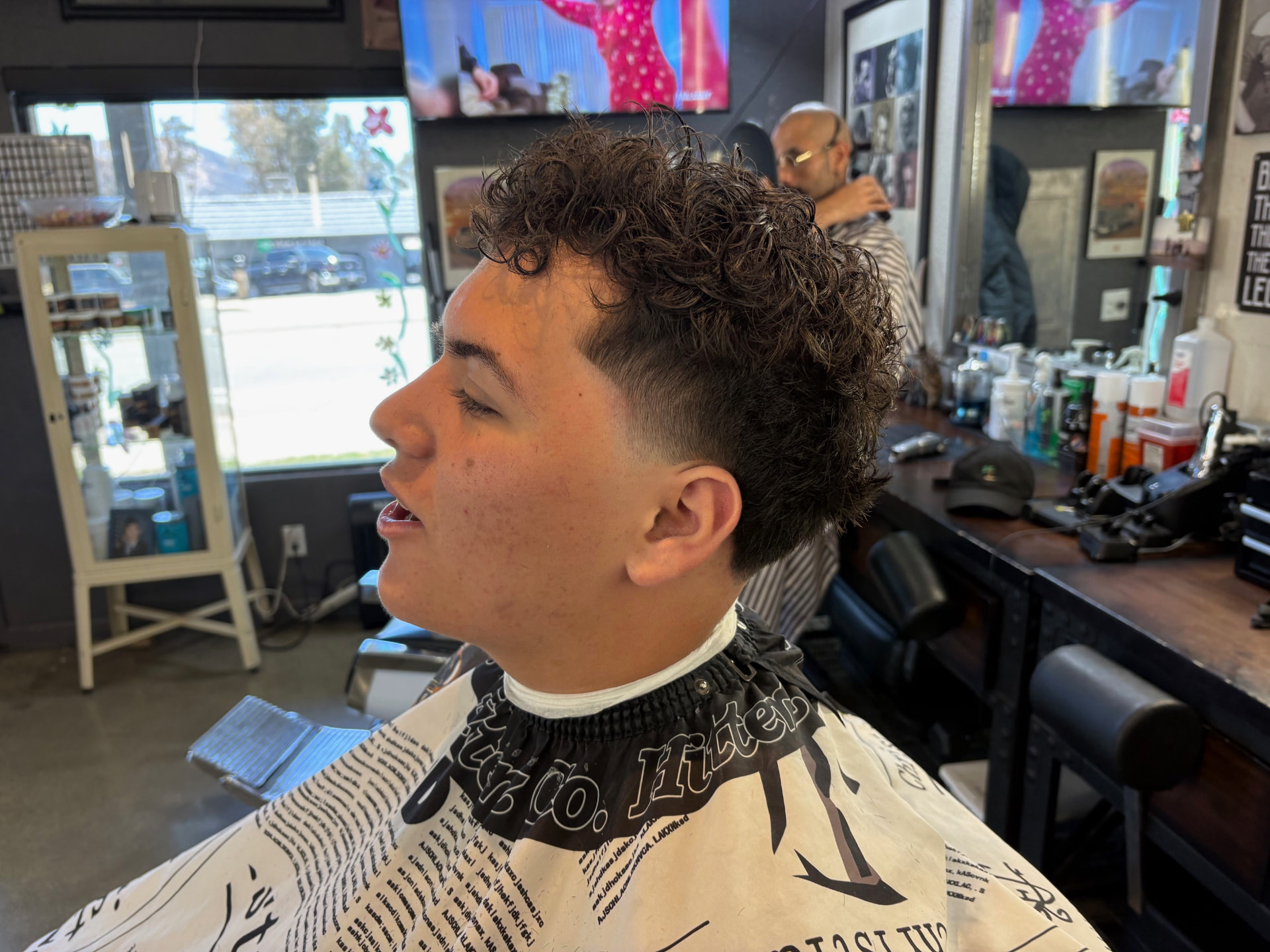 Curly textured haircut with a taper by Kai